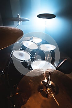 Close-up Drum set in a dark room against the backdrop of the spotlight. Atmospheric background symbol of playing rock or