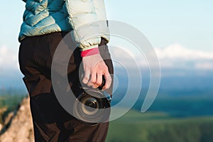 Close-up DSLR camera in the hands of the girl photographer in nature with a camera in hand. Side view