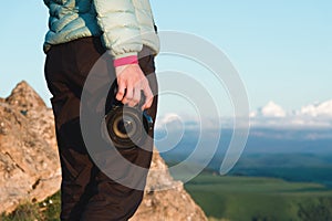 Close-up DSLR camera in the hands of the girl photographer in nature with a camera in hand. Side view