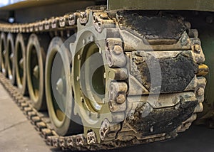 Close-up of dusty caterpillar wheels of military tank