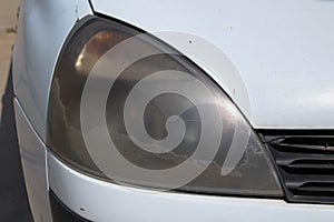 Close-up of dusty headlight on a white car