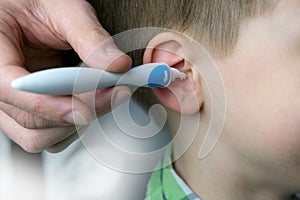 Close-up ear child, kid, adult hand gently cleans the inner ear, Spiral Silicone Earwax Remover blue, modern hygiene concept,