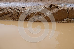 Close-up of earthy and muddy puddle on wet dirt road