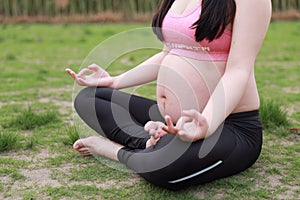 Close-up of Eastern Asian Chiense pregnant woman do yoga sit in meditation , lotus gesture, namaste healthy life