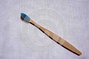 Close up of the Eco-friendly blue bamboo toothbrush on a white linen background. Natural organic bathroom beauty product concept.