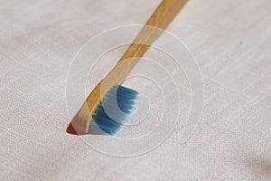 Close up of the Eco-friendly blue bamboo toothbrush on a white linen background. Natural organic bathroom beauty product concept.