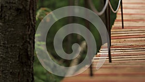 Close up of the edge of hanging wooden bridge on blurred green grass background. Stock footage. Wobbling wooden