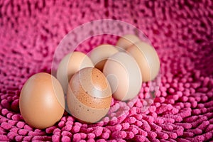 Close-up of Egg with dots and many fresh eggs on Pink fabric background
