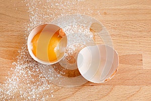 Close up egg, yolk in eggshell, flour on a wooden background