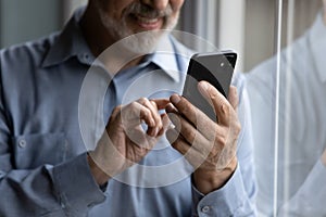 Close up elder middle aged man using smartphone apps.