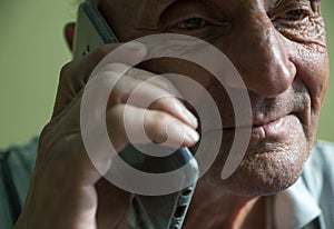Close-up An elderly Caucasian man over 70 years old talking on a smartphone. Selective focus
