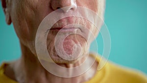 Close-up of an elderly man biting a red apple. Healthy teeth and diet concept