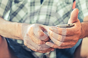 Close up of an elderly man hand using mobile smart phone