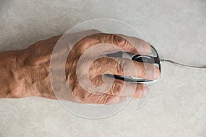 Close-up of an elderly man`s hand on a computer mouse. older people are learning new computer technologies.