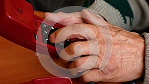 Close-up of an elderly man`s hand dialing 911 on a wired phone. The pensioner calls the rescue service. The signal indicates a sup