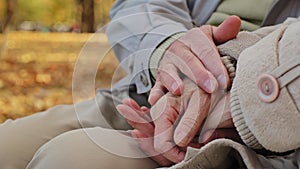 Close-up elderly married couple gently stroking hands of each other romantic date in autumn park aged spouses enjoying