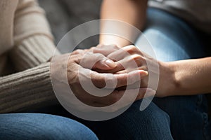 Close up of elderly mom and adult daughter hold hands