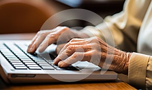 Close-up of an elderly person\'s hands typing on a laptop keyboard