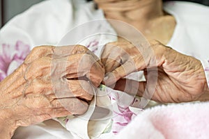 Elderly woman fasten buttons on dress , progressive brain disorder ,Close up hand photo