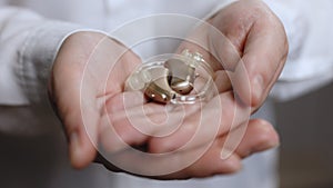 Close up of elderly woman holding hearing aid equipment. The hearing aid lies in the female palm. Hearing aid concept