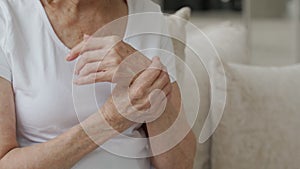 Close-up elderly woman suffering from arthritis of the hands sitting on the couch. The concept of mental health and care