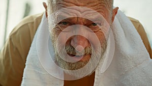Close up elderly wrinkled Caucasian man with towel looking at camera tired training sportsman sportive exercise outside