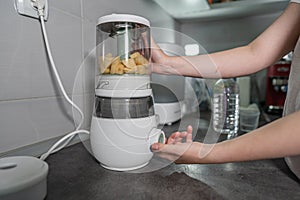 Close up on the electric blender in hand of unknown woman holding it on the kitchen counter preparing potato mash meal