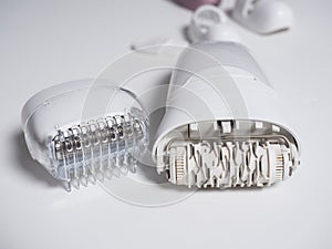 Close-up of the electric epilator for hair removal of white color on a white background. Next to the additional nozzle. Beauty