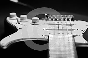 Close-up of an electric guitar on a black background. Monochrome photography.