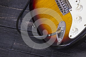 Close up electric guitar connected with a cable on wood