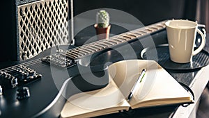 Close-up, electric guitar and notepad, concept of musical creativity.