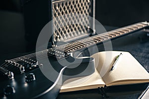 Close-up, electric guitar and notepad, concept of musical creativity.