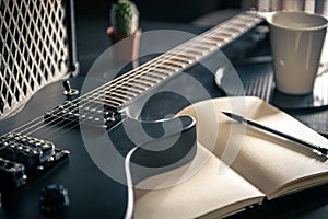 Close-up, electric guitar and notepad, concept of musical creativity.