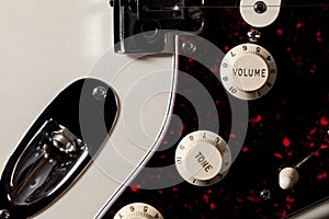 Close-up of electric guitar volume and tone control knobs.