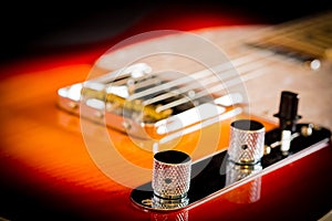 Close up of a electric guitar volume and tone knobs and bridge