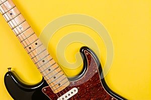 Close-up of electric guitar on yellow background, with copy space