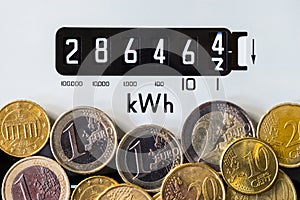 Close-up of electric meter and Euro coins. Energy crisis.