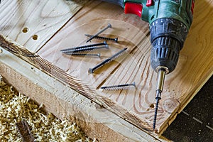 Close up of electric screwdriver with some screws laying on old