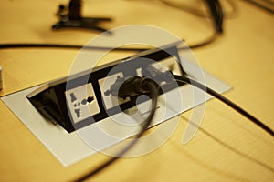 Close-up of an electrical plug in a socket on a desk