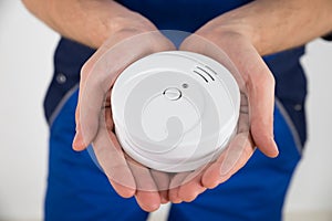 Close-up Of Electrician Holding Smoke Detector