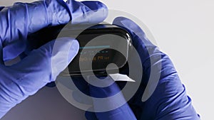Close up of electronic pulse oximeter in the hands of doctor, wearing blue latex gloves