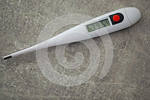 Close-up electronic thermometer for measuring body temperature on a gray background