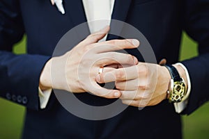 close-up of elegance male hands. man dressed in blue suit and white shirt standing over green nature background. groom or