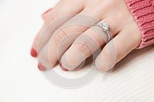 Close up of an elegant engagement diamond ring on woman finger with pink sweater winter clothe