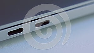 Close up of elegant modern laptop details. Action. Concept of modern technologies, USB port of a computer lying on white