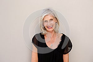 Close up elegant older lady smiling against wall