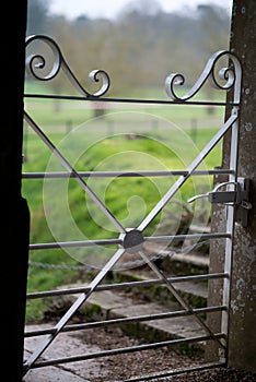 Close up of an elegant white metal garden gate with stone gateposts