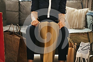 Close up on elegant woman sitting on divan with shopping bags