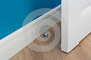 Close-up elements of the interior of the apartment. Metal chrome door stopper on laminate floor