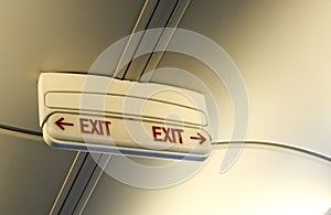 close up of emergency door exit sign with red arrow on the ceiling of the aircraft